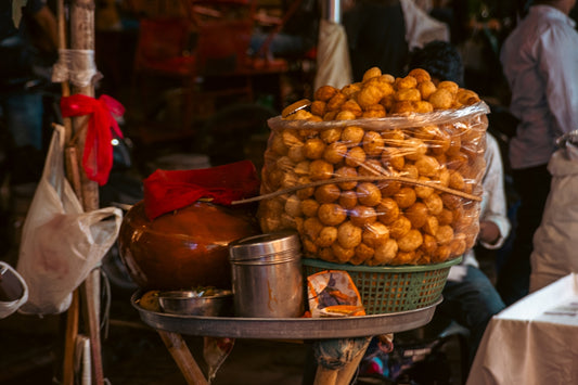 Street vendor selling fried snacks in a basket.